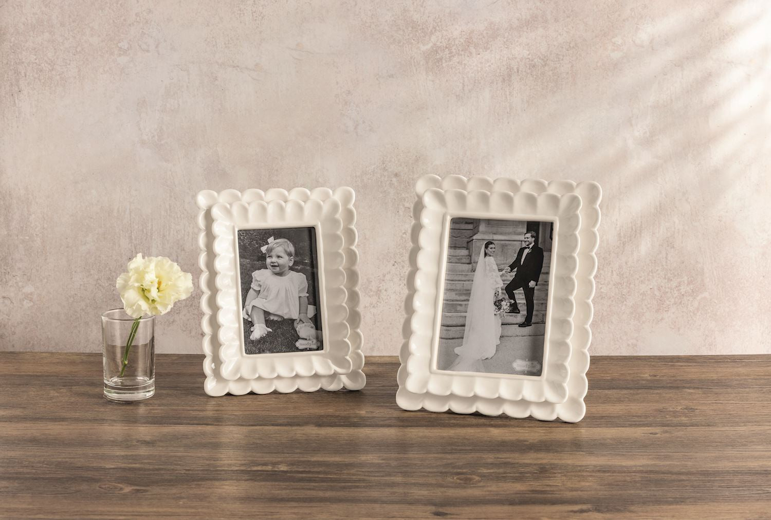 Two decorative white picture frames on a wooden surface with a neutral background
