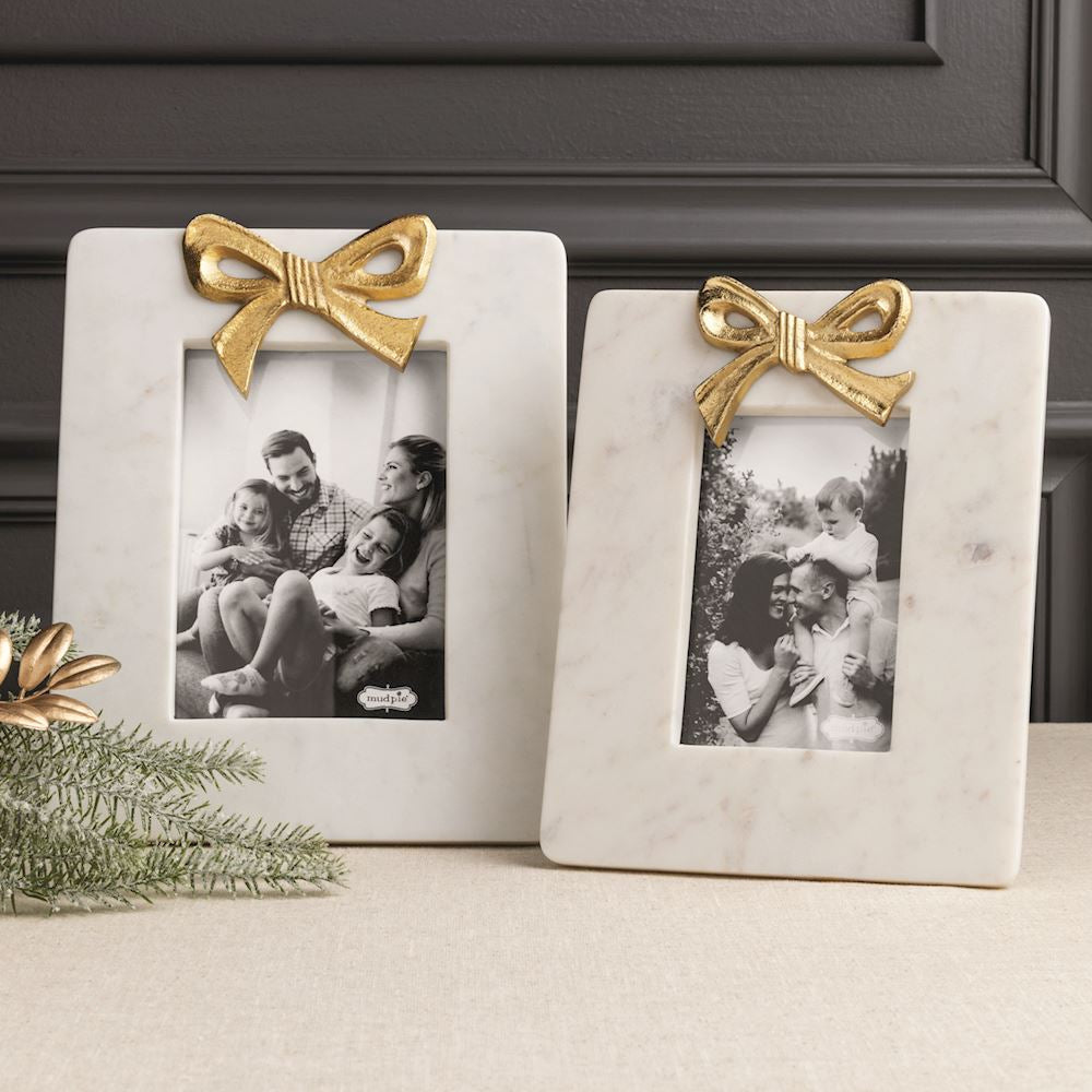2 different sized marble photo frames with gold bows on a decorated table