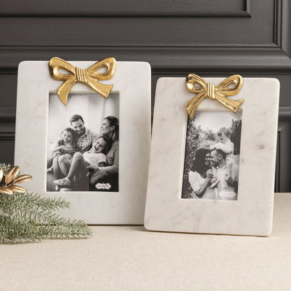 2 different sized marble photo frames with gold bows on a decorated table