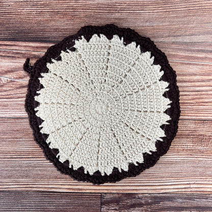 off-white round crocheted pot holder with brown boarder. 