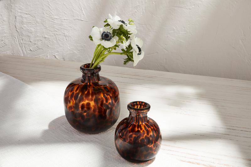 2 sizes of Tortoise Vases set on a table, the larger vase has white flowers in it
