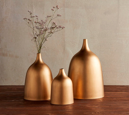 3 sizes of Brass Vases arranged on a table, medium vase has florals in it