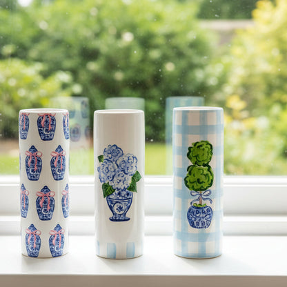 Three ceramic vases with decorative patterns on a windowsill with a blurred green outdoor background.