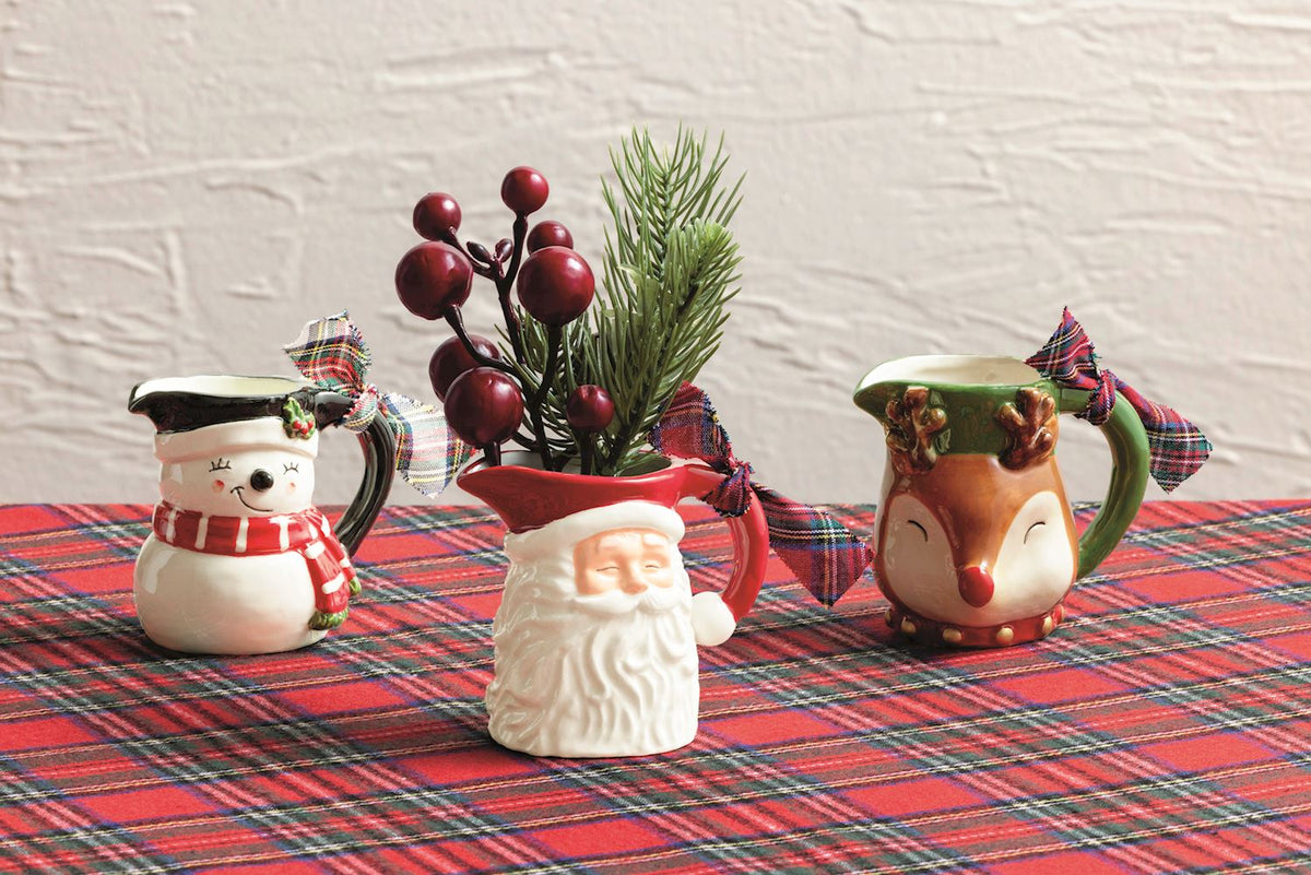 small pitcher vases on a tartan table cloth, santa pitcher vase has greenery in it