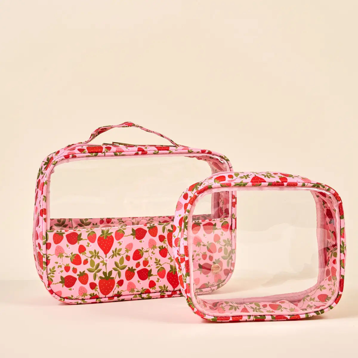 Two clear cosmetic bags with strawberry pattern on a beige background