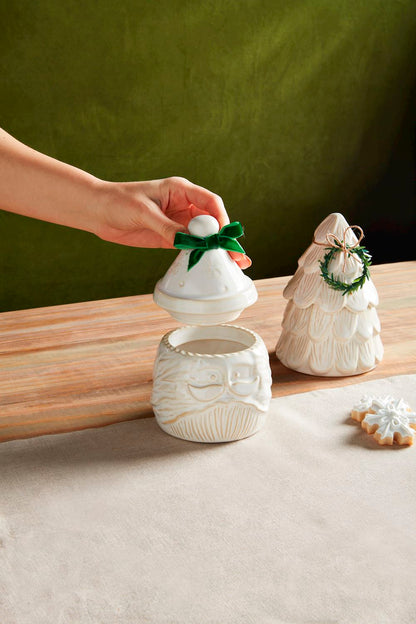 tree and santa canisters set on a table, a hand is taking the lid off of the santa canister.