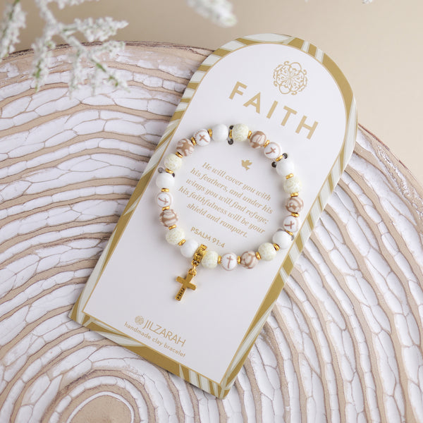 ivory faith bracelet with gold cross on card packaging.
