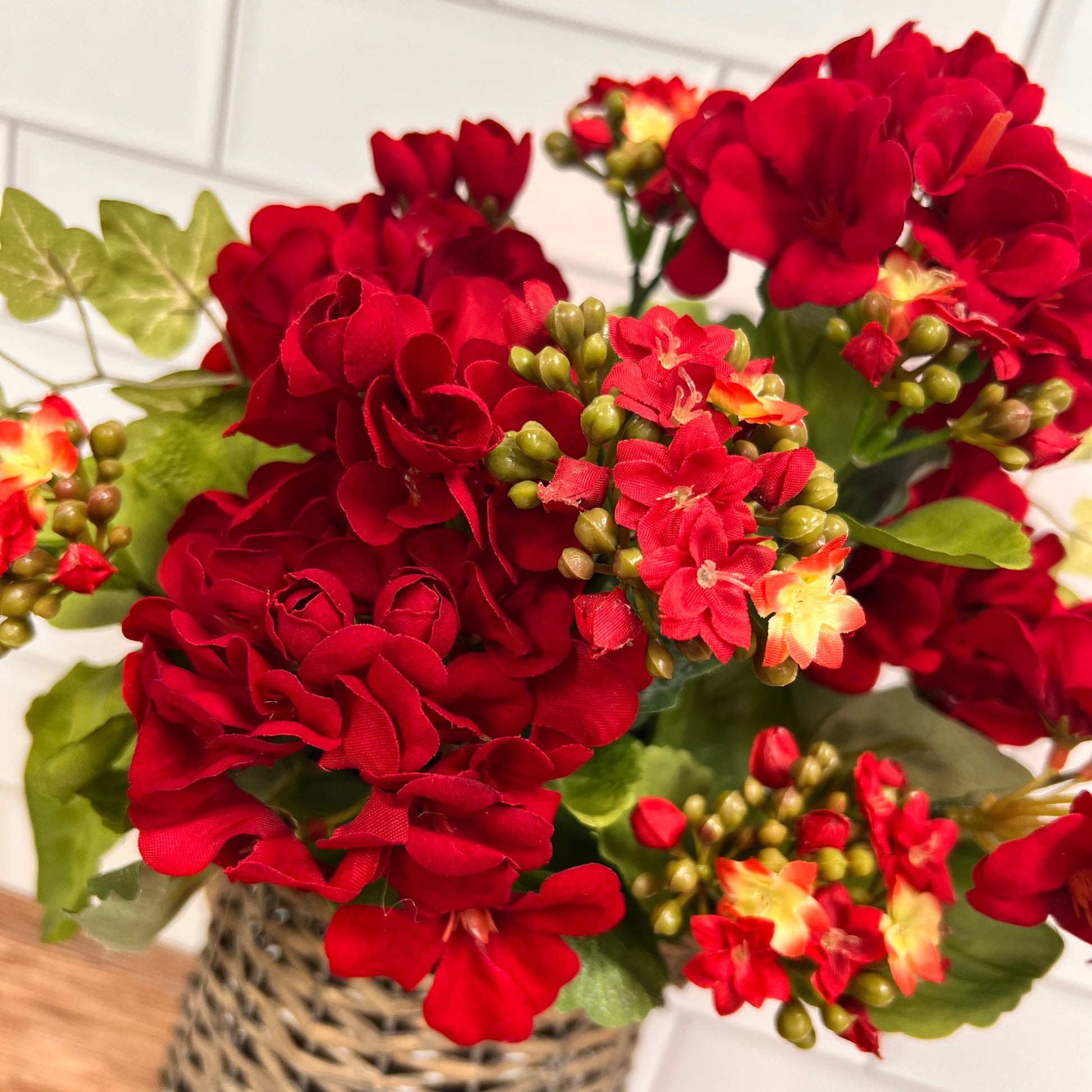 close-up of red geraniums in a woven vase.
