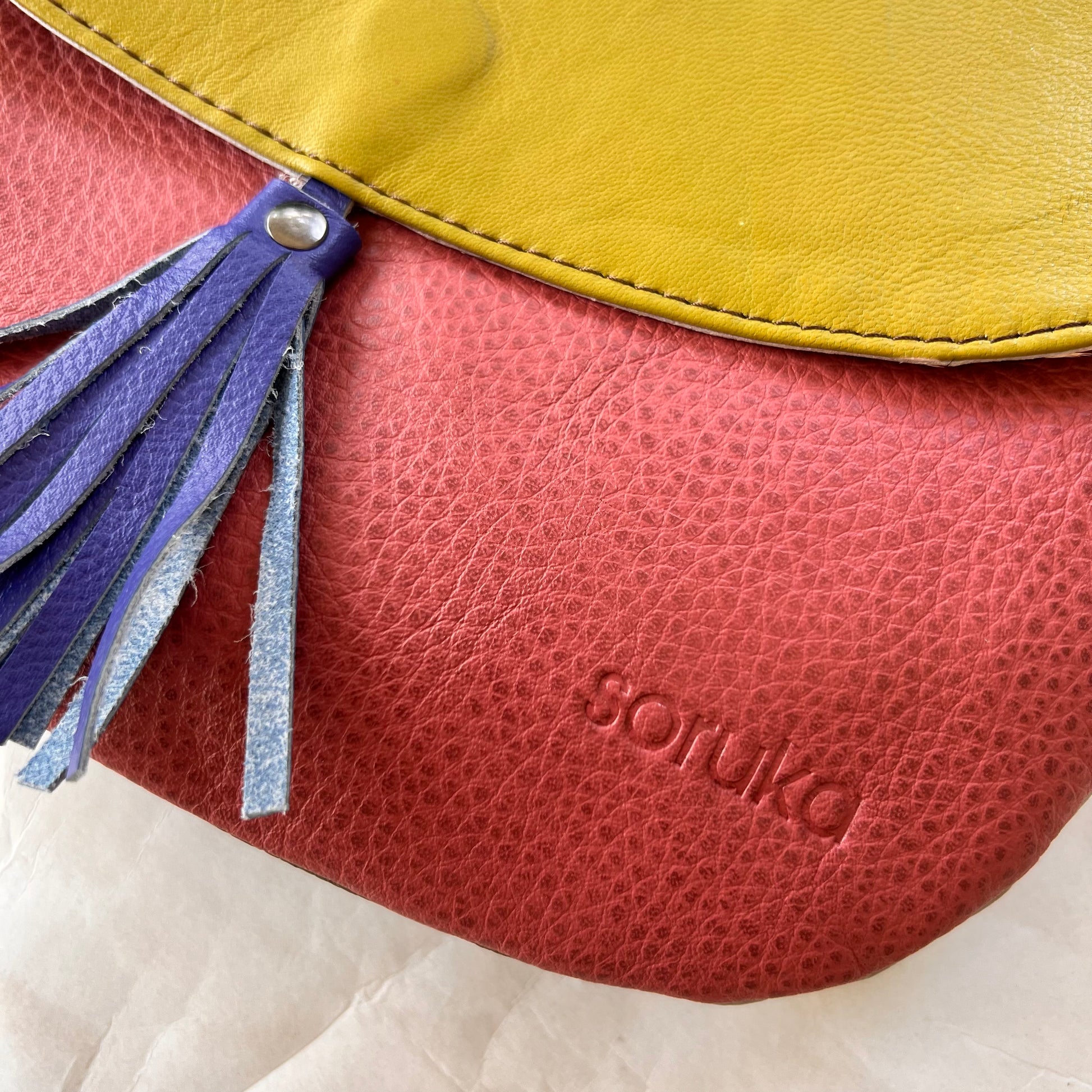 close-up of lola bag with lime green flap with royal tassel over a dusty rose body..