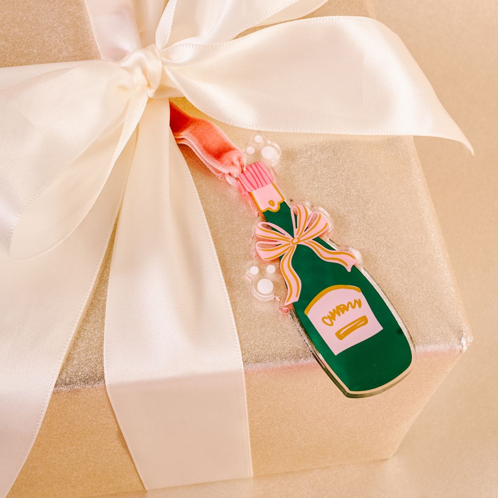 flat acrylic ornament in the shape of a green champagne bottle tied on a package