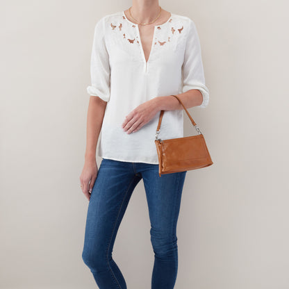 person wearing jeans and white top with truffle cadence on a short strap on their arm.