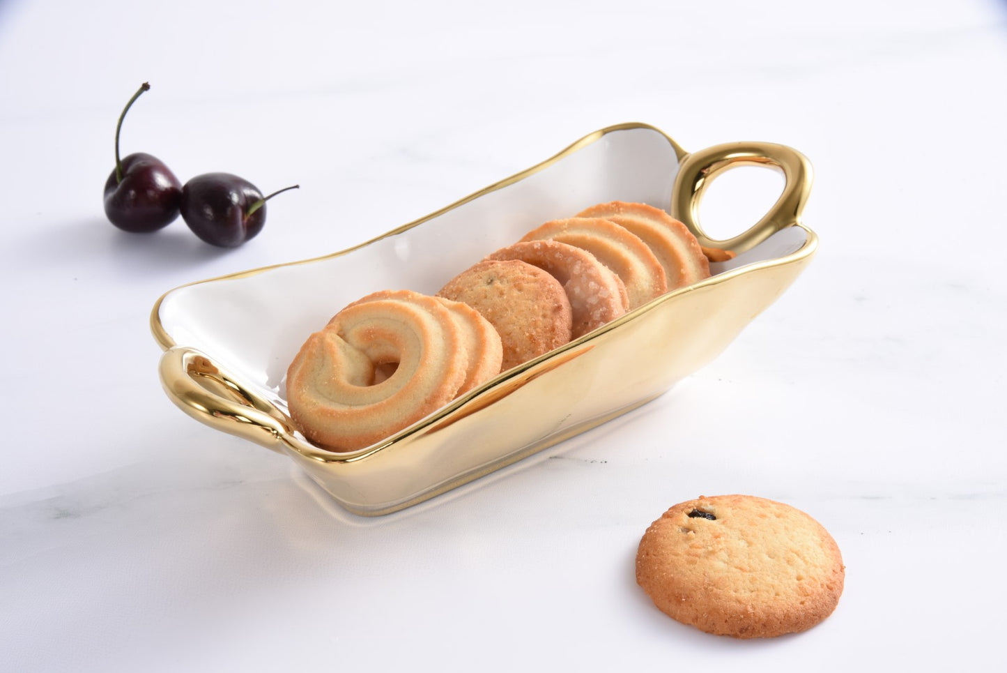 Gold rim bowl with cookies and cherries on a white background