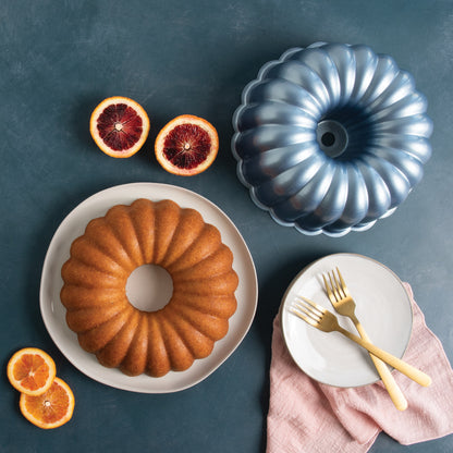 top view of table with baked bunt cake, Party Bundt Pan, and plates and forks arranged on it