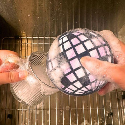 hands using disco ball kitchen sponge to wash dishes.