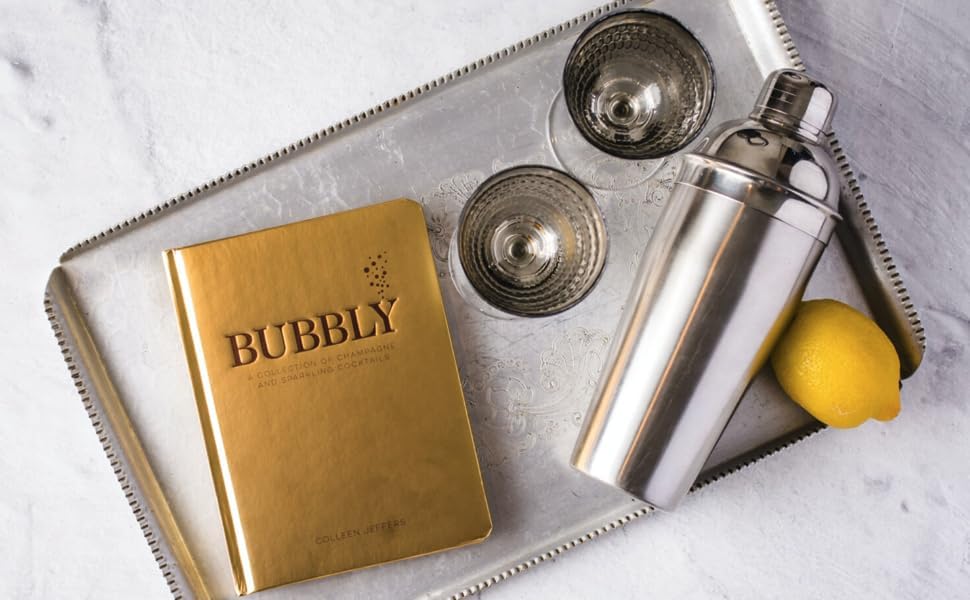 bubbly book set on a silver tray with glasses, a cocktail shaker and a lemon.