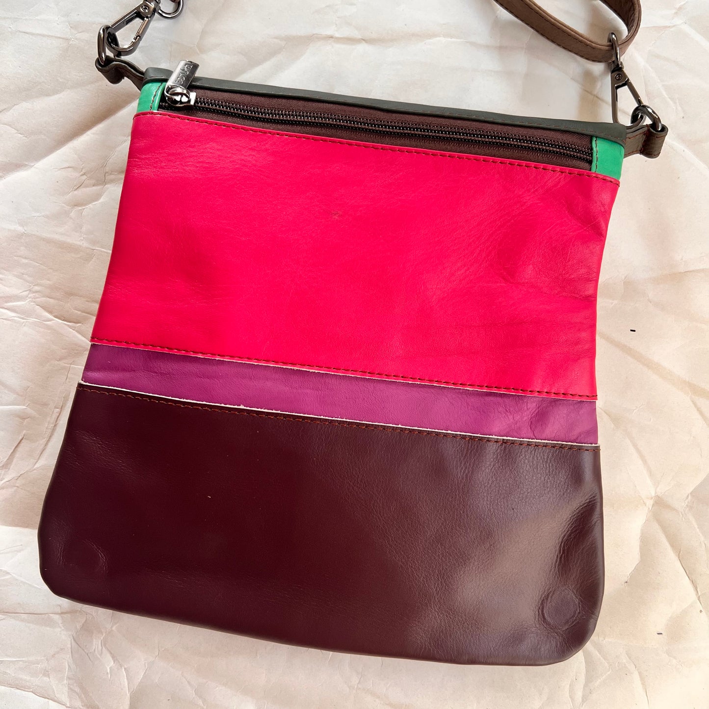 greta bag with stripes of pink and purples and a zipper across the top.