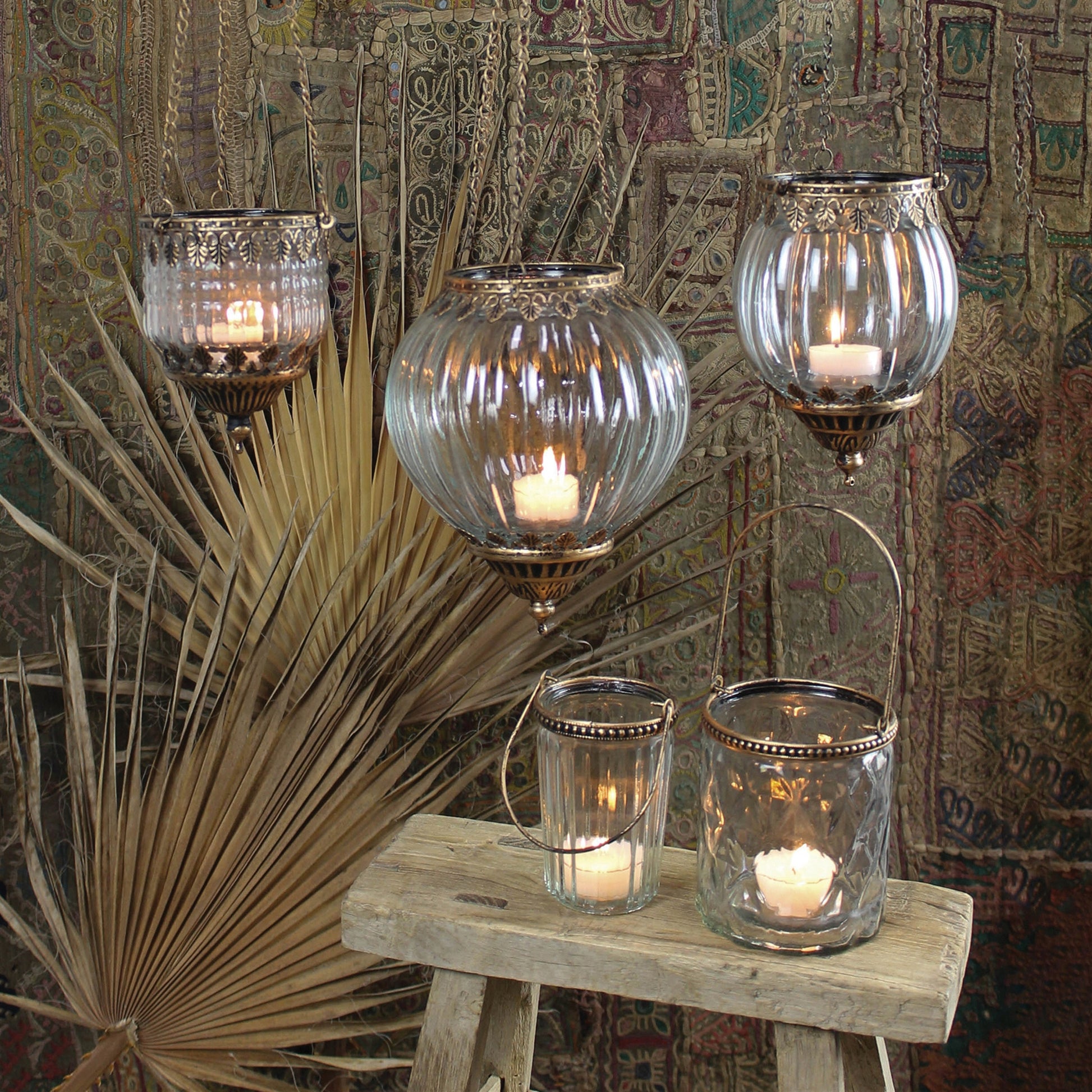 grouping of 5 assorted glass and metal lanterns filled with lit candles.