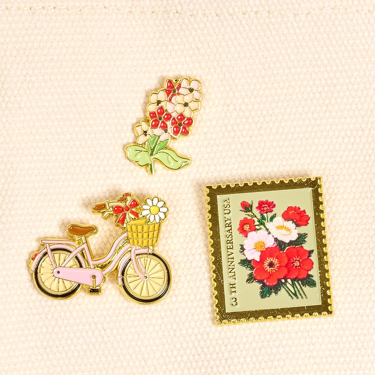 Pin with bicycle, flowers, and matching stamp on a textured beige background