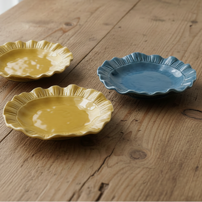 1 blue and 2 mustard colored ruffle plates set on a wooden table