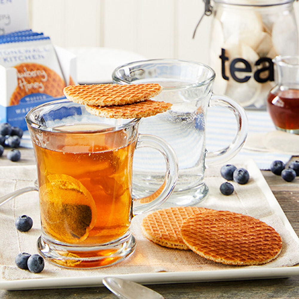 blueberry waffle cookies arranged on a table with mugs of tea.