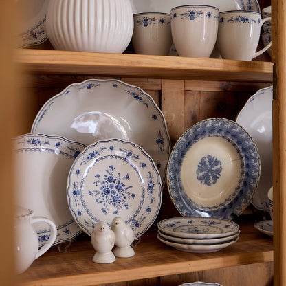 Collection of ceramic plates and cups with blue floral patterns on a wooden shelf.
