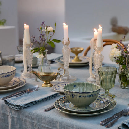 Elegant table setting with candles, floral arrangements, and olive green plates with blue floral designs