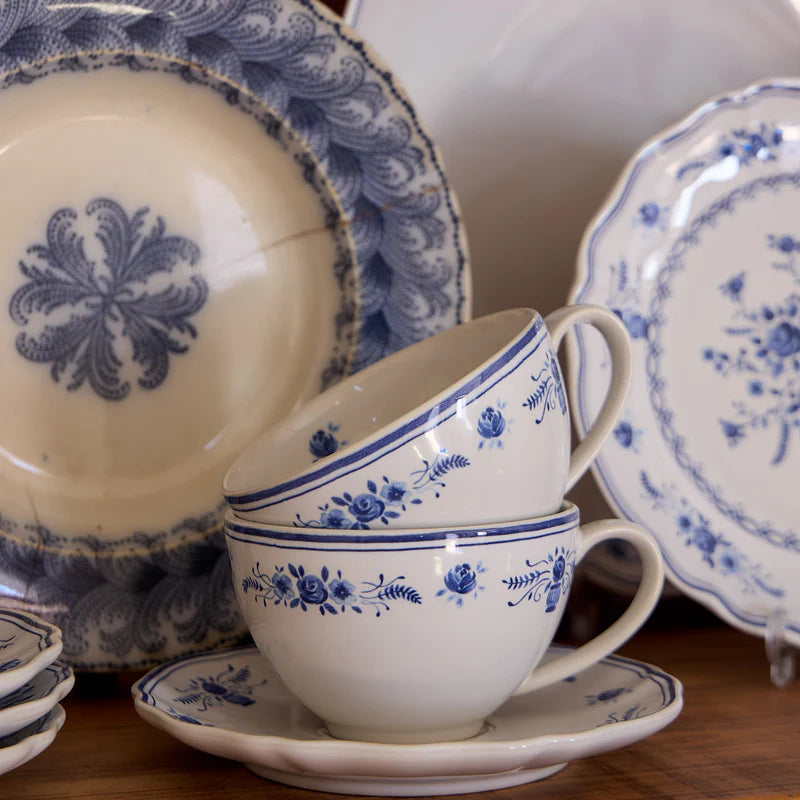 Set of blue and white patterned teacups and saucers on a wooden surface.