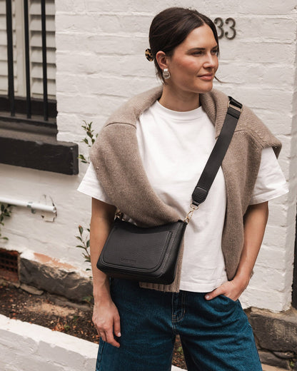 view of person wearing jeans and a tee shirt holding black Linda Crossbody Bag