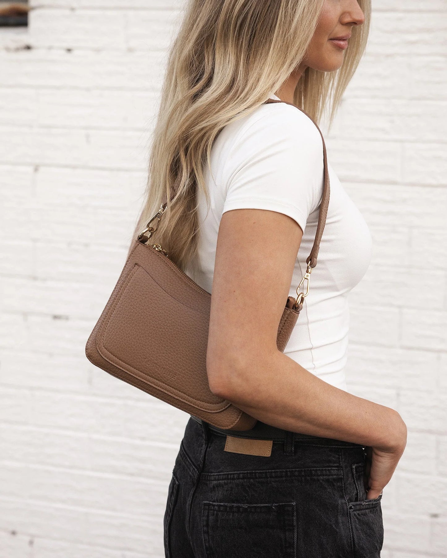 person wearing jeans and a tee shirt carrying caramel Linda Crossbody Bag