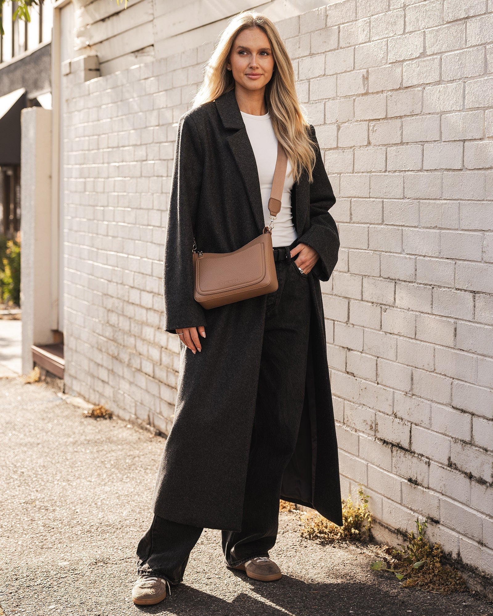 person wearing long black coat with caramel Linda Crossbody Bag worn as a crossbody