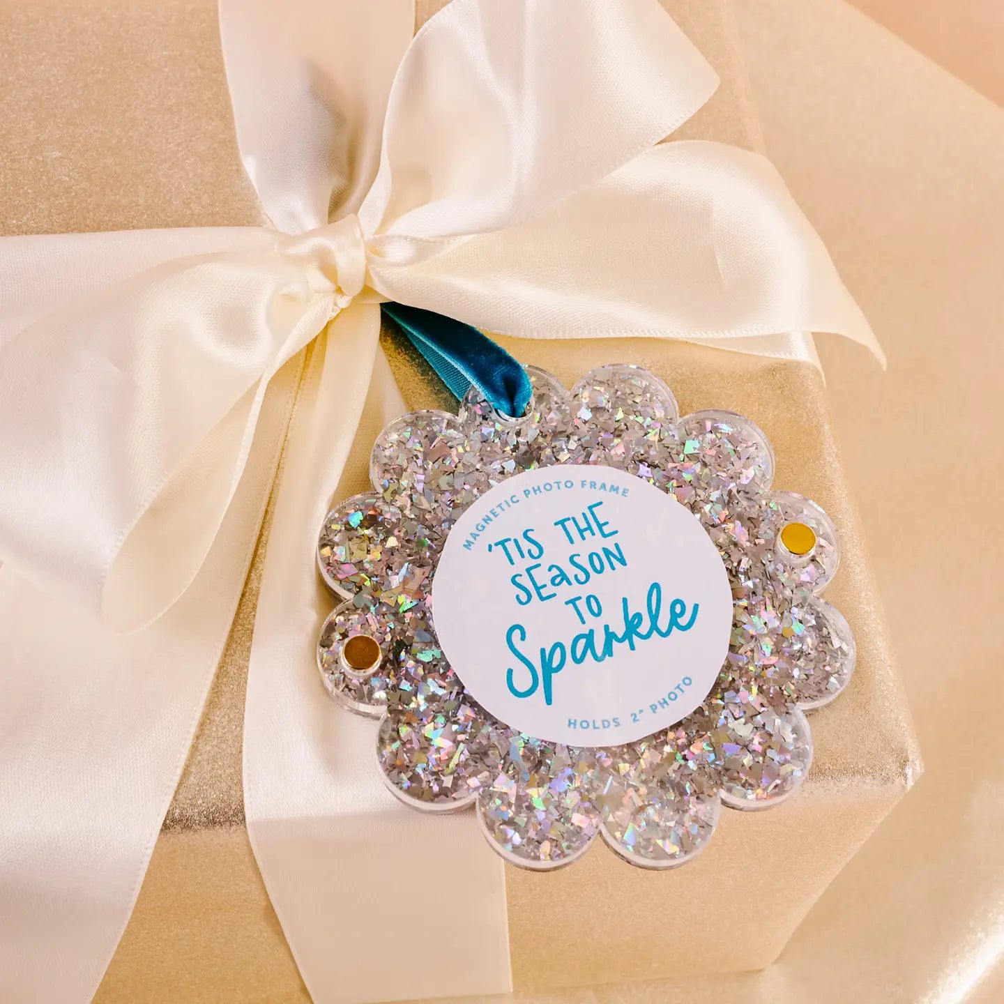silver glitter Scalloped Acrylic Frame Ornament tied in an ivory bow of a wrapped gift