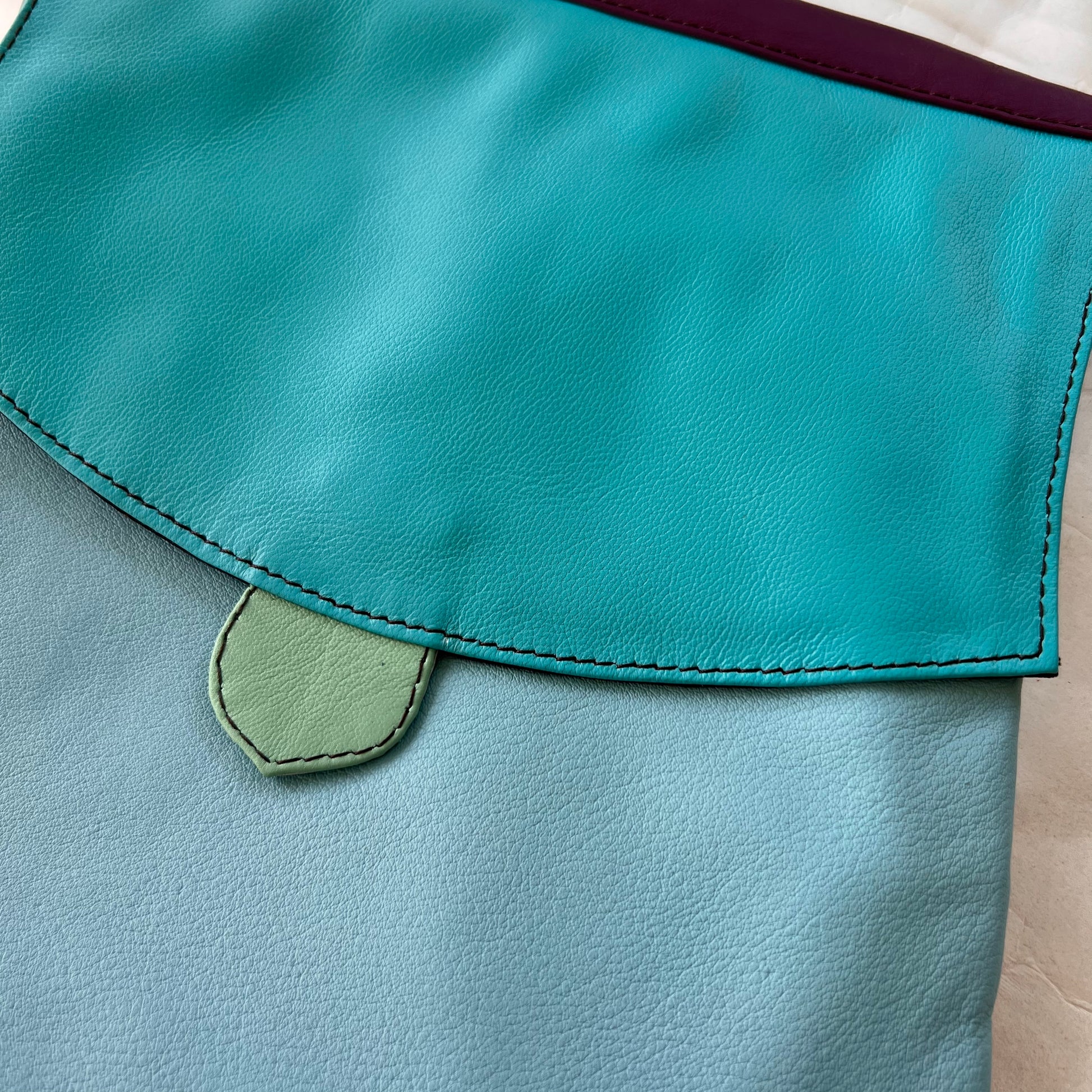 close-up of greta bag with bright blue flap over light blue body.