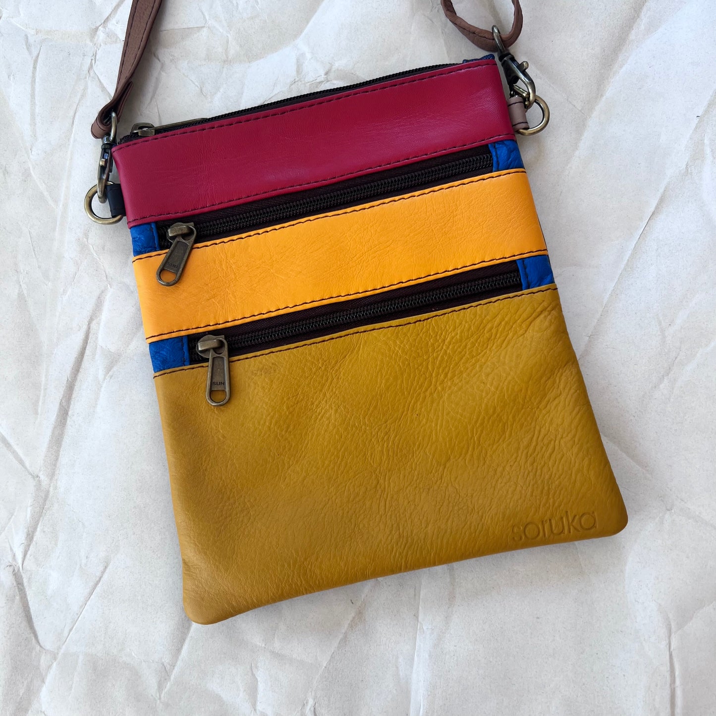 flat rectangular bag with top zipper and 2 zipper pockets color blocked in yellow and red.