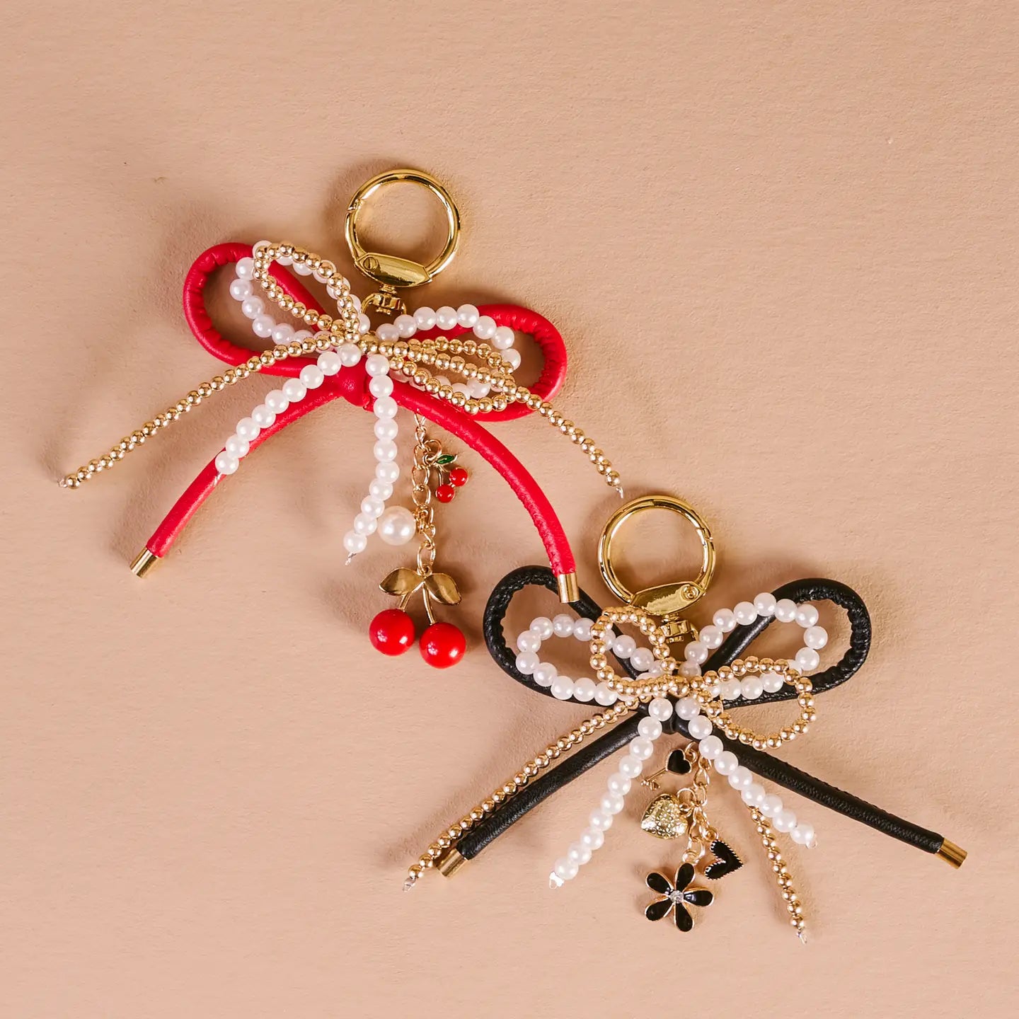 one red and one black Layered Bows Bag Charms on a beige background