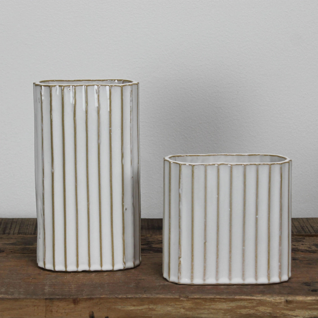 Two ceramic vases with ribbed texture on a wooden surface.