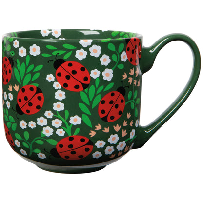 green mug with white flowers and red ladybugs printed on it