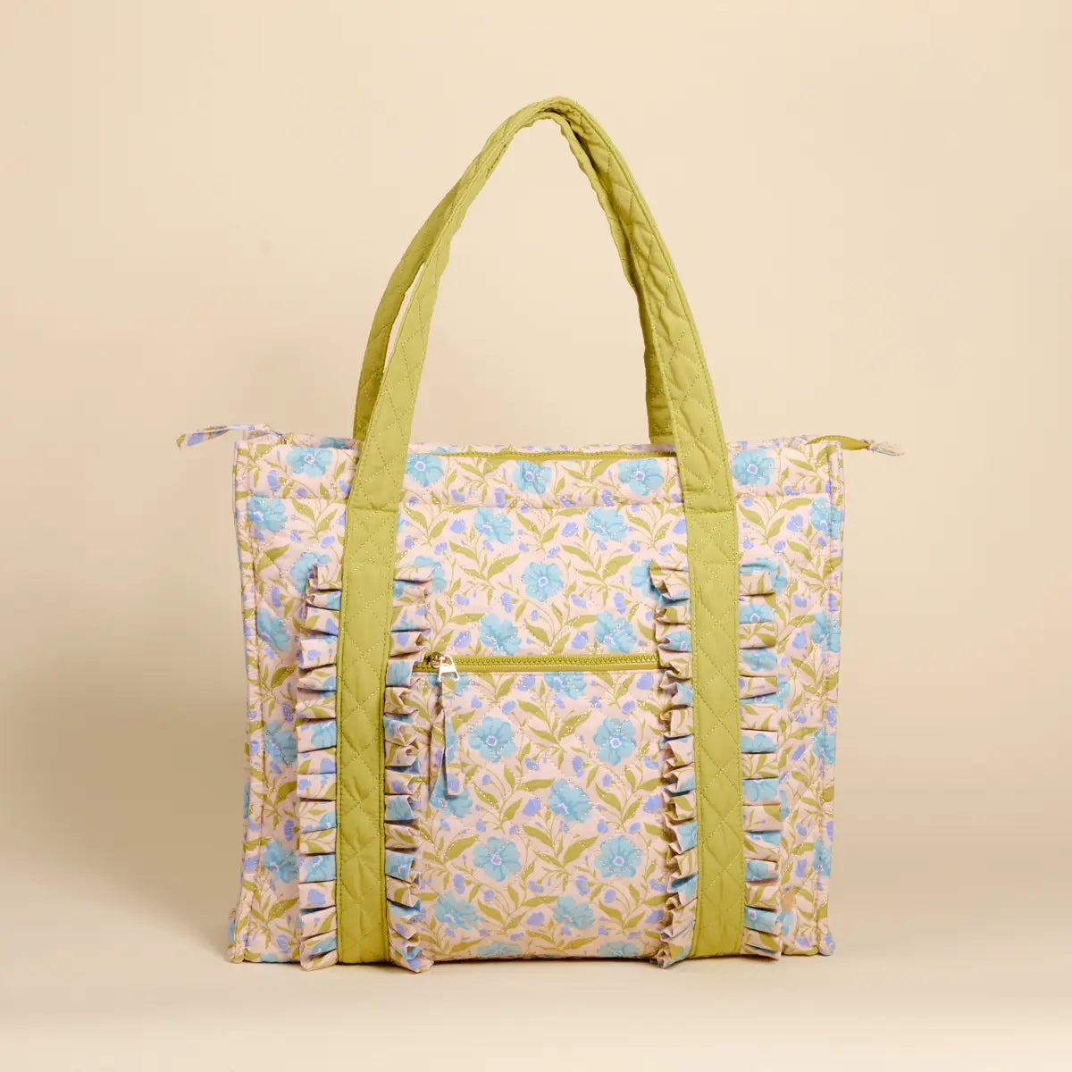 Floral patterned tote bag with green handles on a beige background