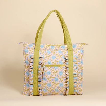 Floral patterned tote bag with green handles on a beige background