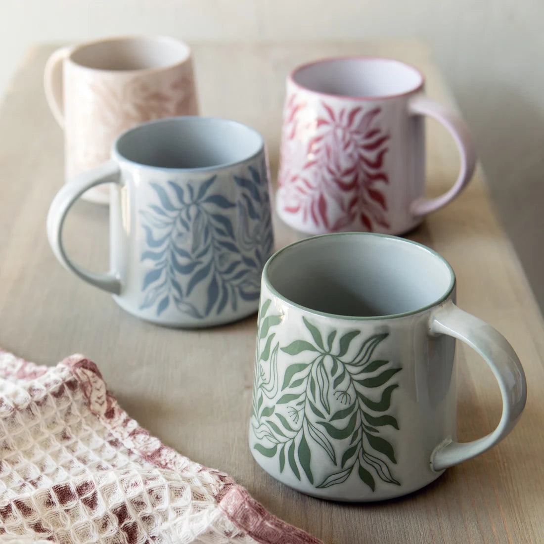 Four patterned mugs on a wooden surface