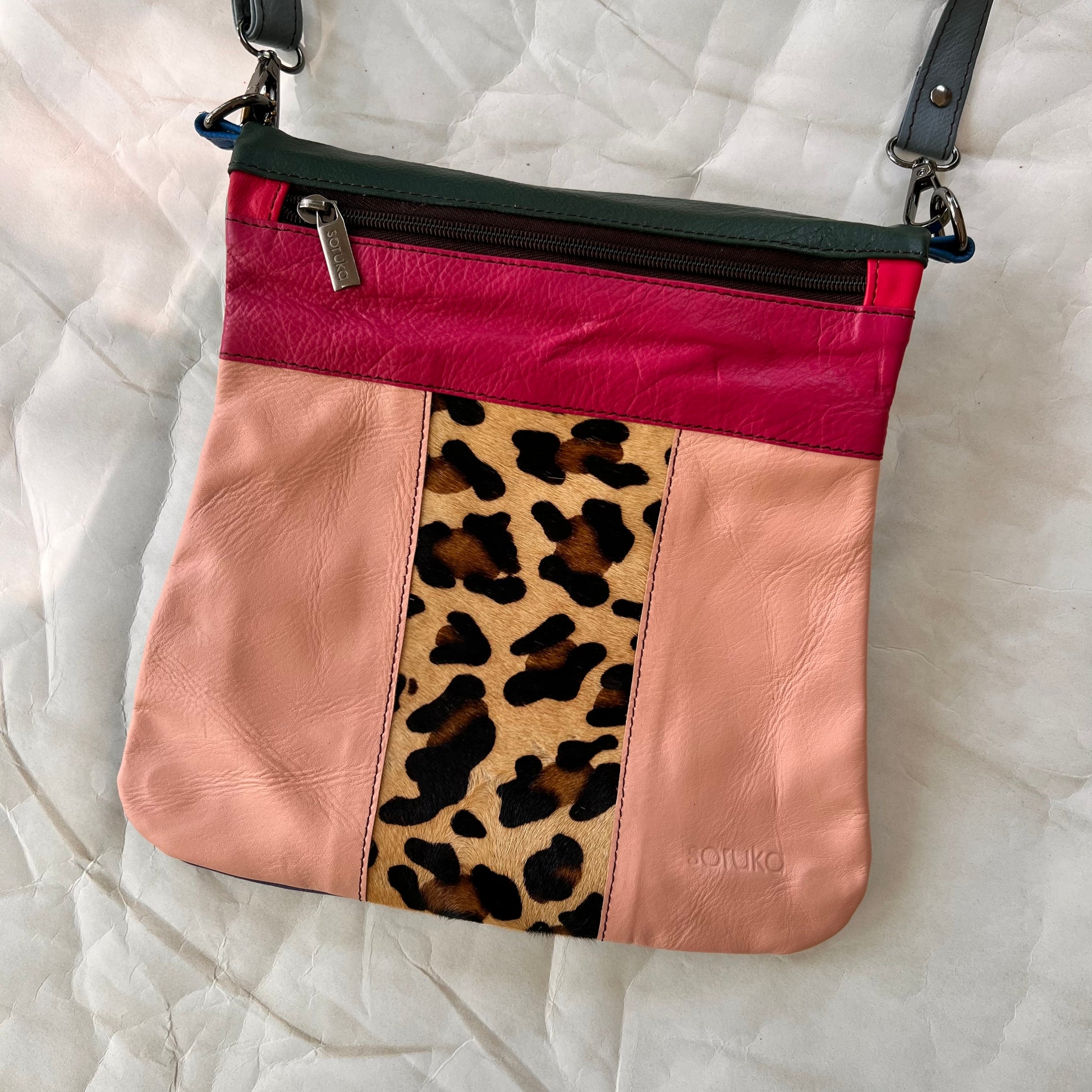 peach greta bag with animal print block in the center with pink stripe and zipper across the top.