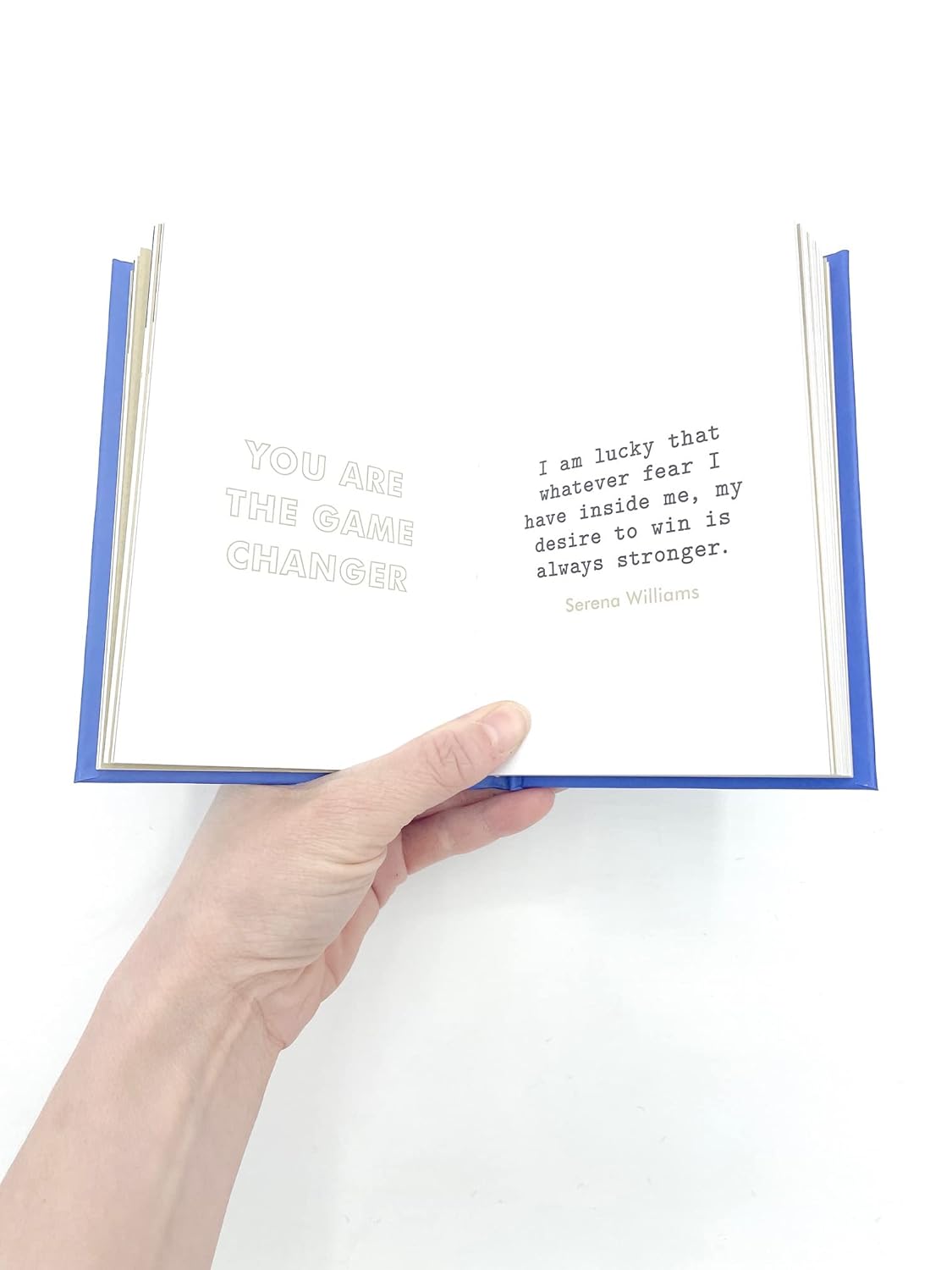 Hand holding an open book with a quote on a white background