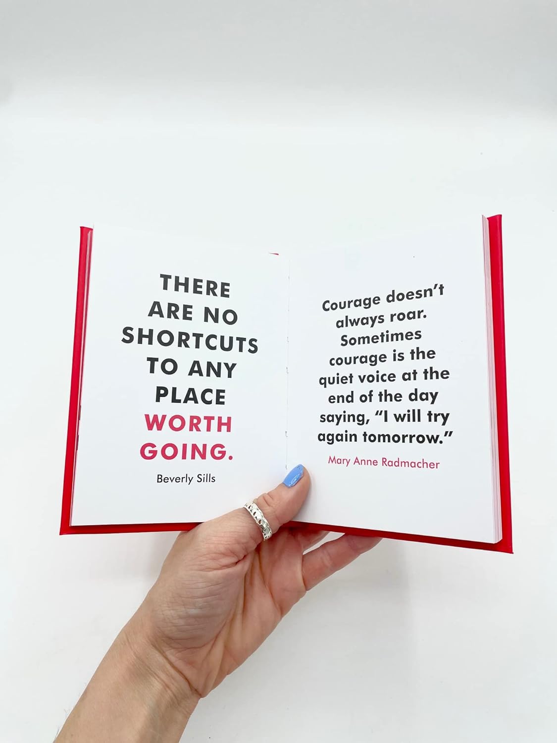 Hand holding an open book with motivational quotes on a white background
