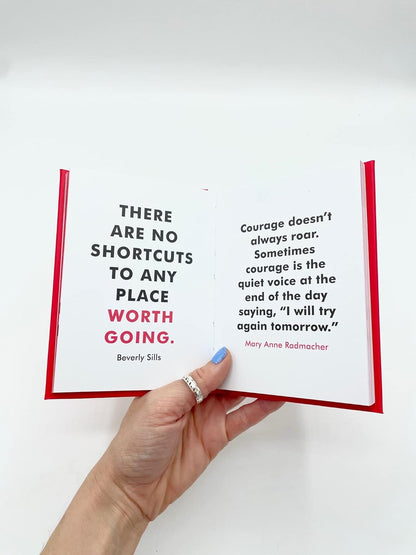 Hand holding an open book with motivational quotes on a white background
