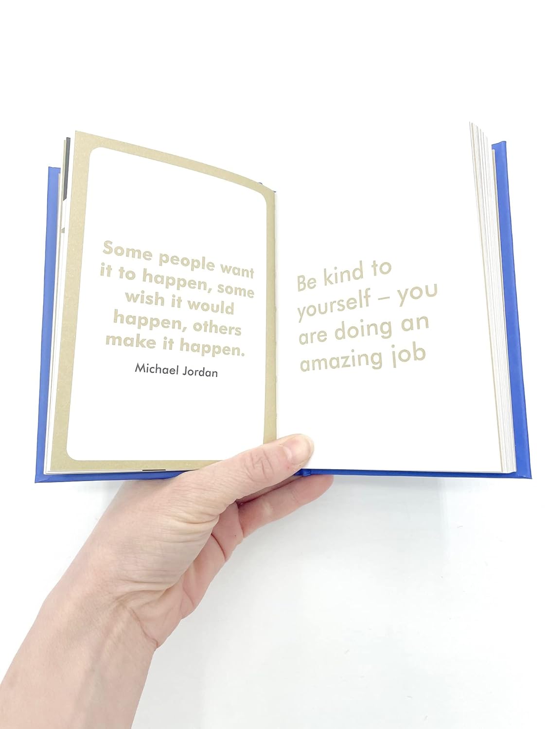 Hand holding an open book with motivational quotes on a white background