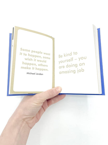 Hand holding an open book with motivational quotes on a white background