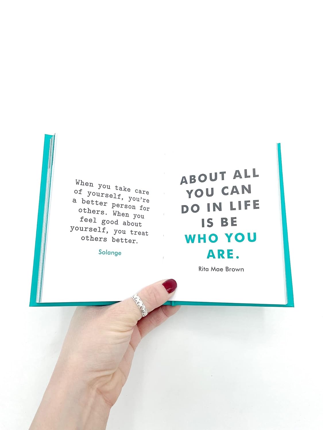 Hand holding an open book with a quote on a white background