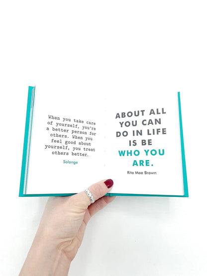 Hand holding an open book with a quote on a white background