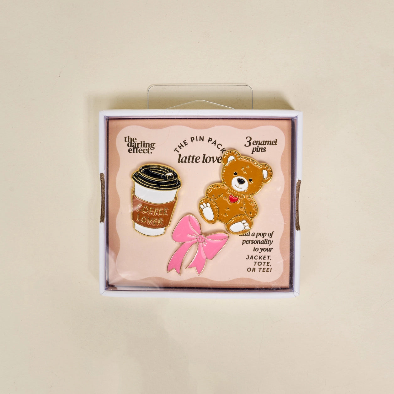 Set of three enamel pins in a box with a teddy bear, coffee cup, and pink bow design.