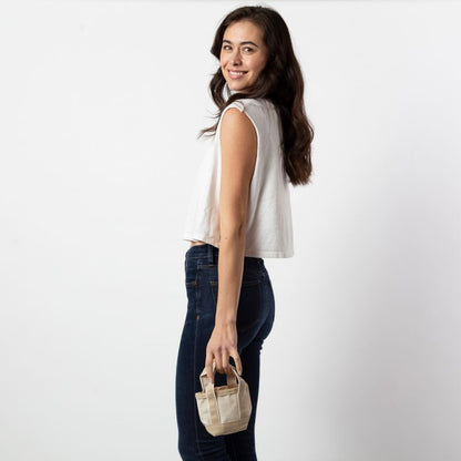 person wearing jeans and a white top holding a mini tote bag