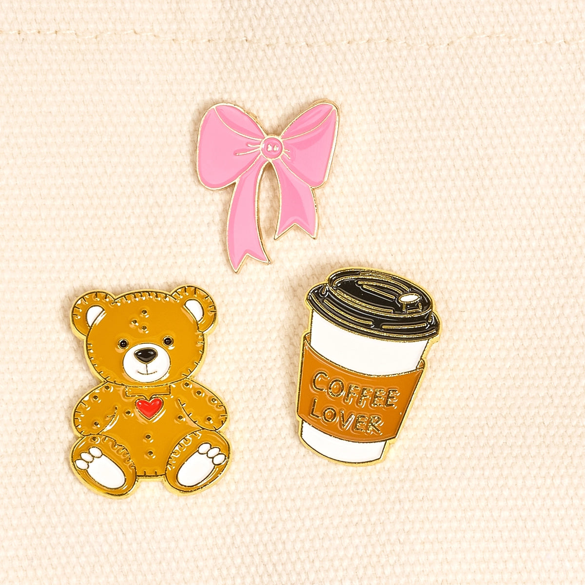 3pins including a pink bow, teddy bear, and coffee cup with 'Coffee Lover' text on a beige background.